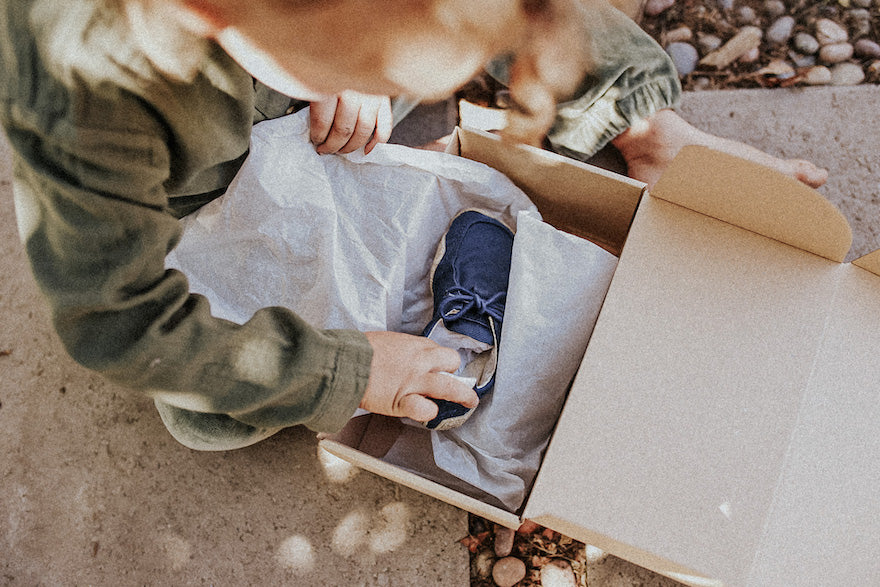 A child unwraps the blue Wildling model Saker from a shoe box.