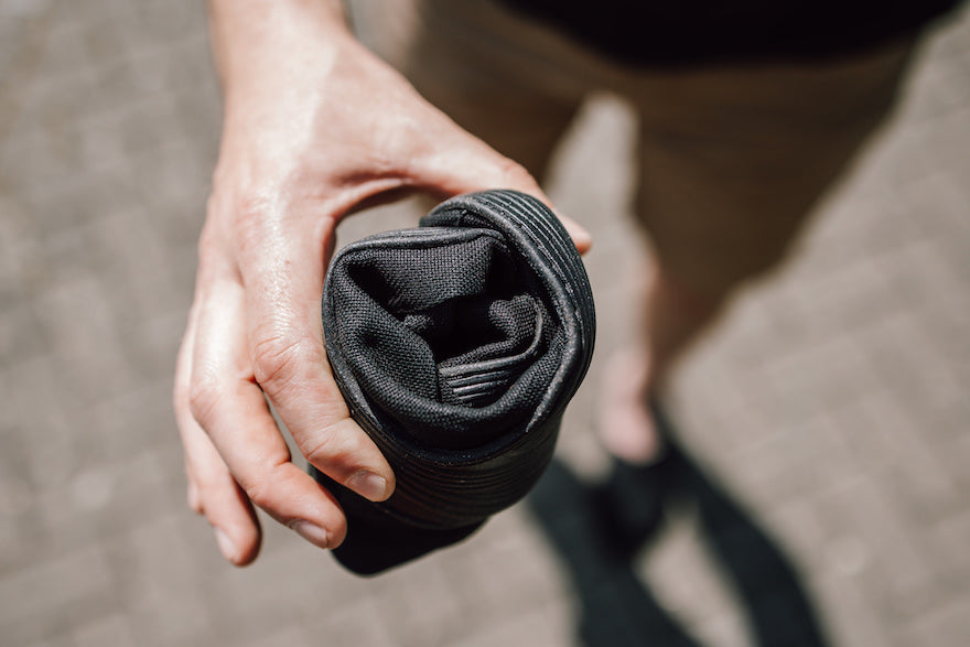 A person is holding a rolled up black shoe made of washi.